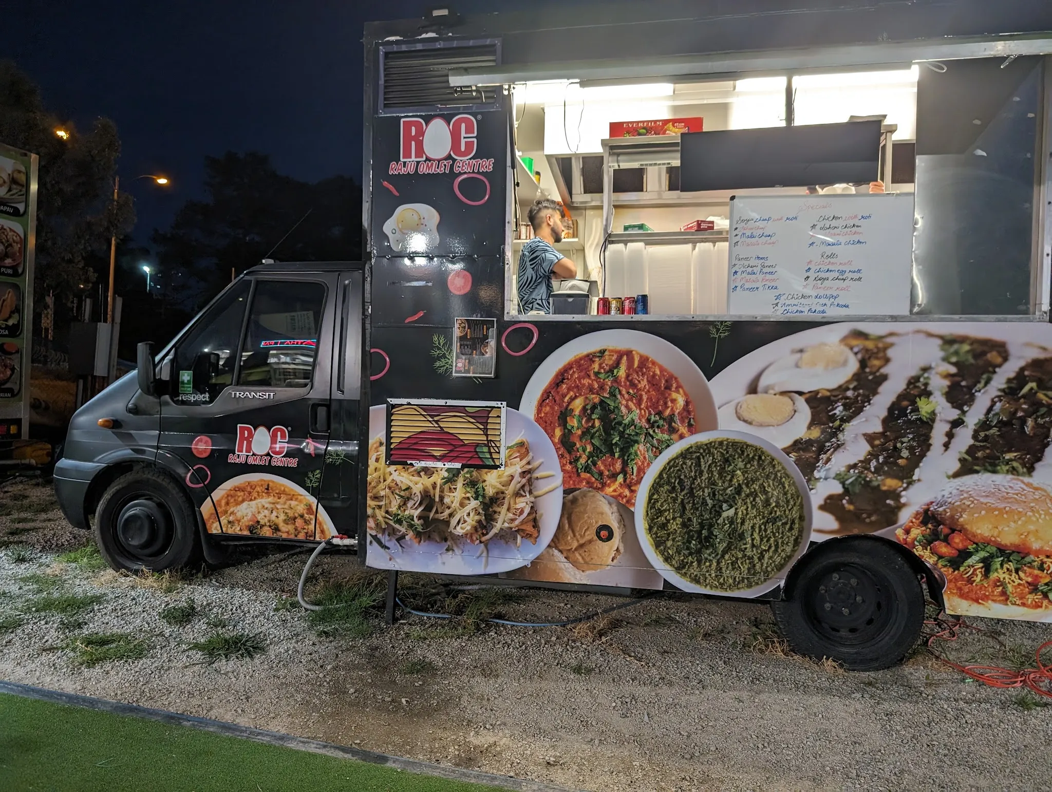 The ROC food truck lit up at night with its serving hatch open and a vendor preparing food inside.