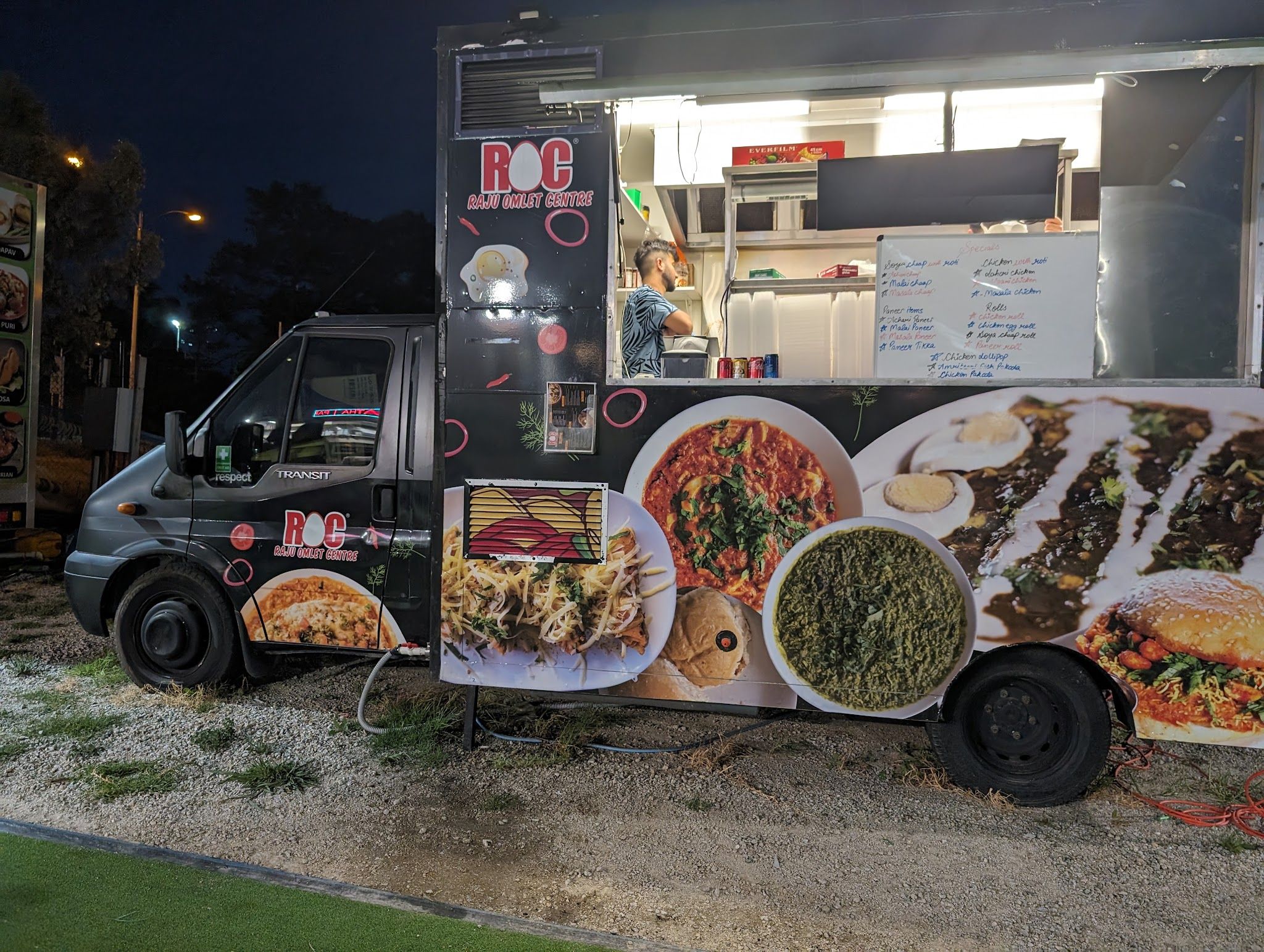 Raju Omlet Centre food truck lit up at night with vendor at the serving window
