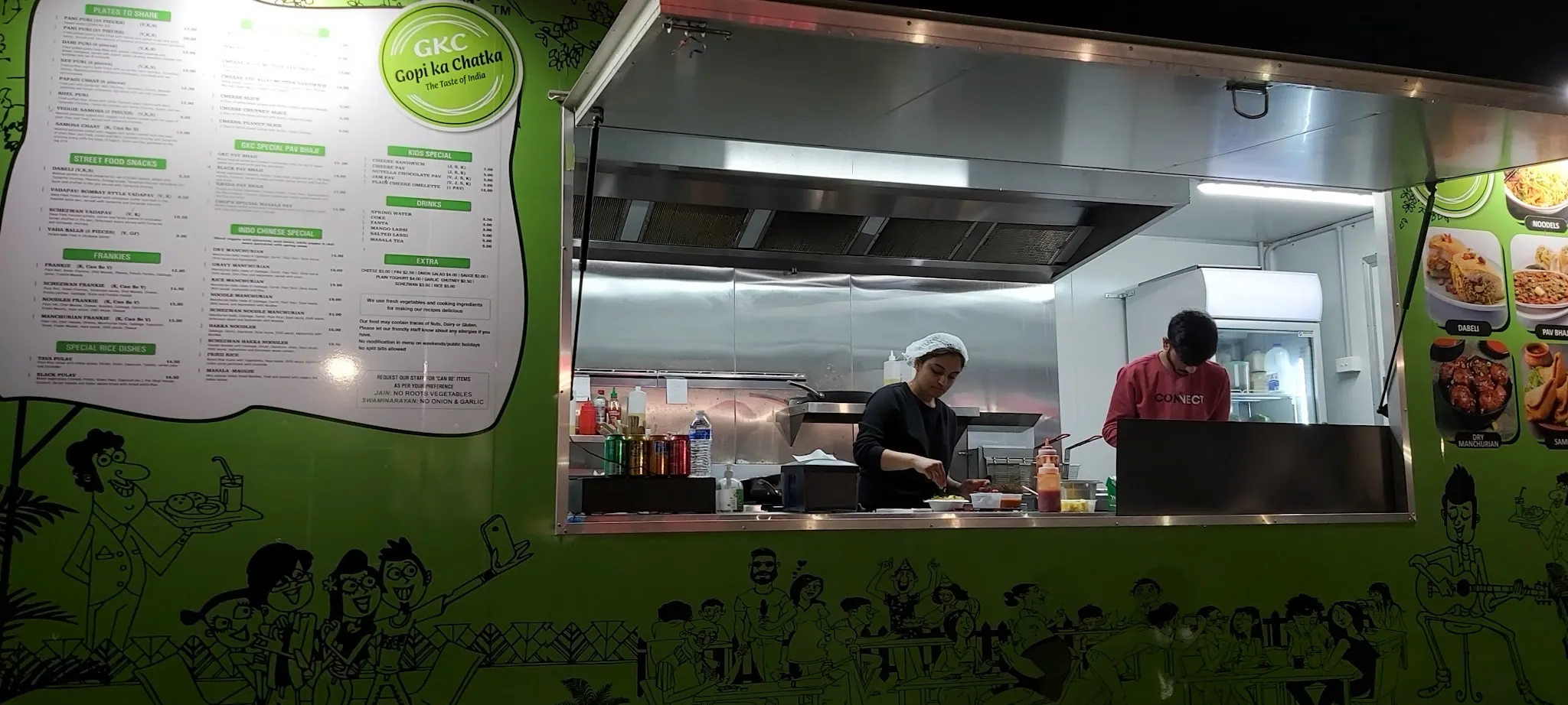Staff inside the GKC truck preparing food at stainless steel counters.